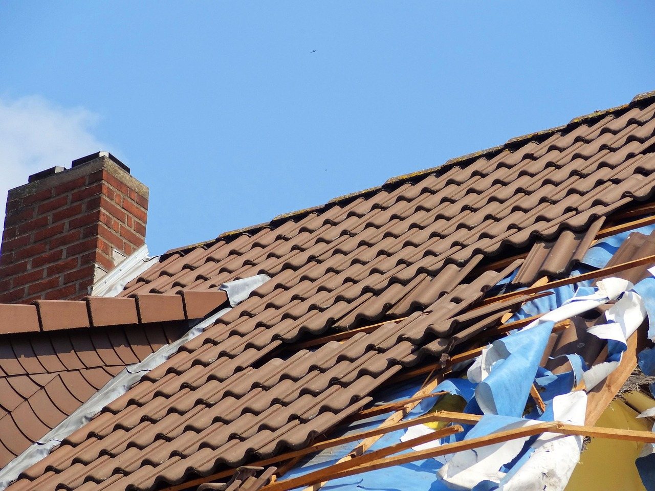 Wind-damaged roof ridge under an emergency tarp