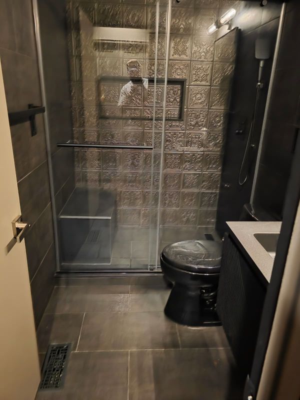 Powder bath with dark walls and a geometric floor by JDG Concrete & Construction