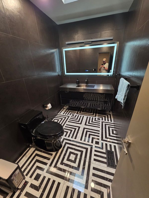 Geometric tile floor and black fixtures by JDG Concrete & Construction