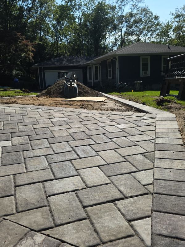 Cobble-bordered patio behind the house by JDG Concrete & Construction