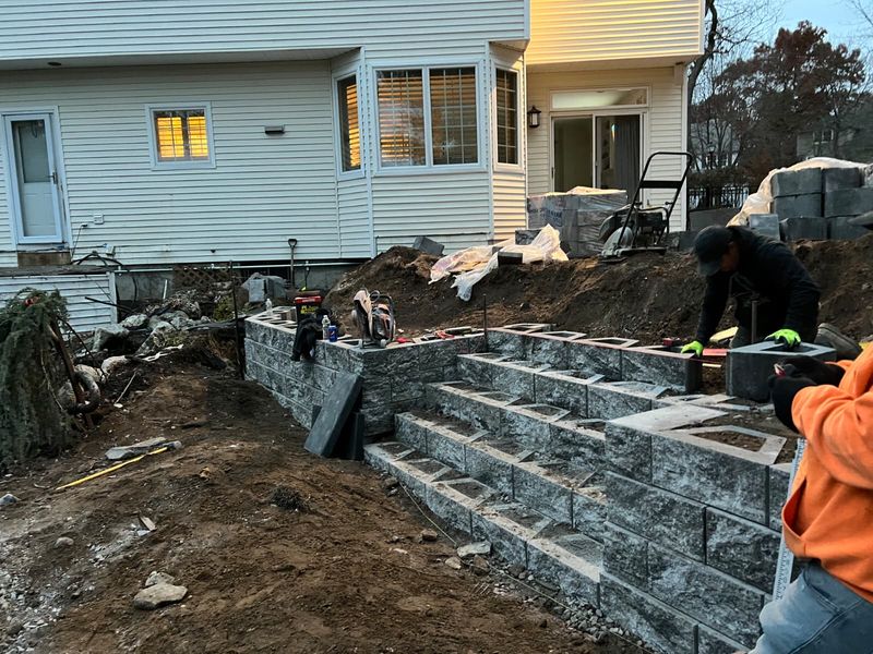 Fire pit patio with a low seating wall by JDG Concrete & Construction