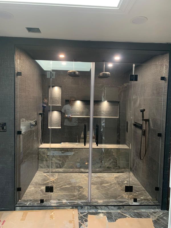Shower niche and rain head behind the glass by JDG Concrete & Construction