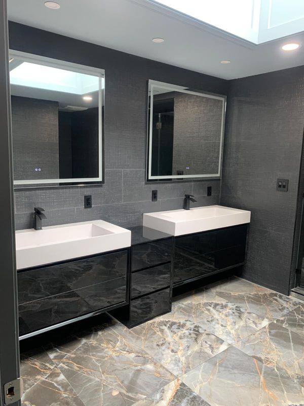 Double vanity with backlit mirrors by JDG Concrete & Construction