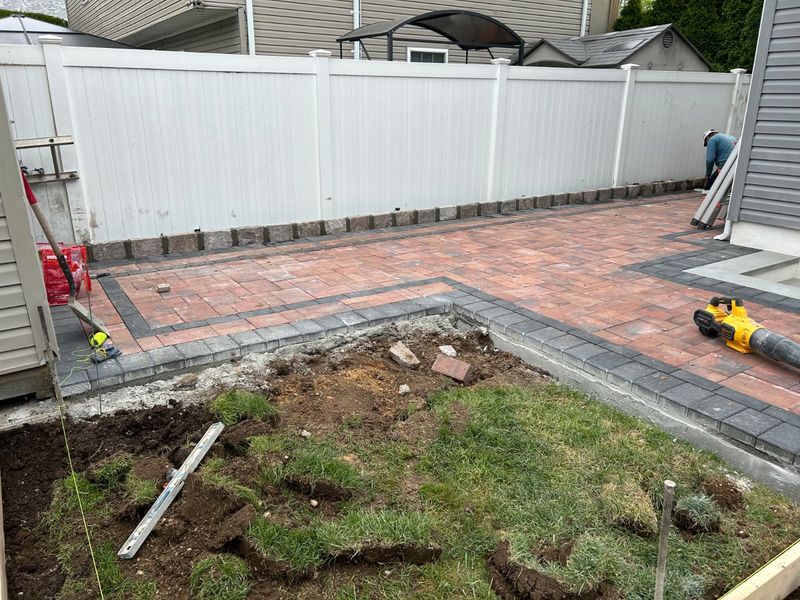 Patio with a brick-red accent band by JDG Concrete & Construction