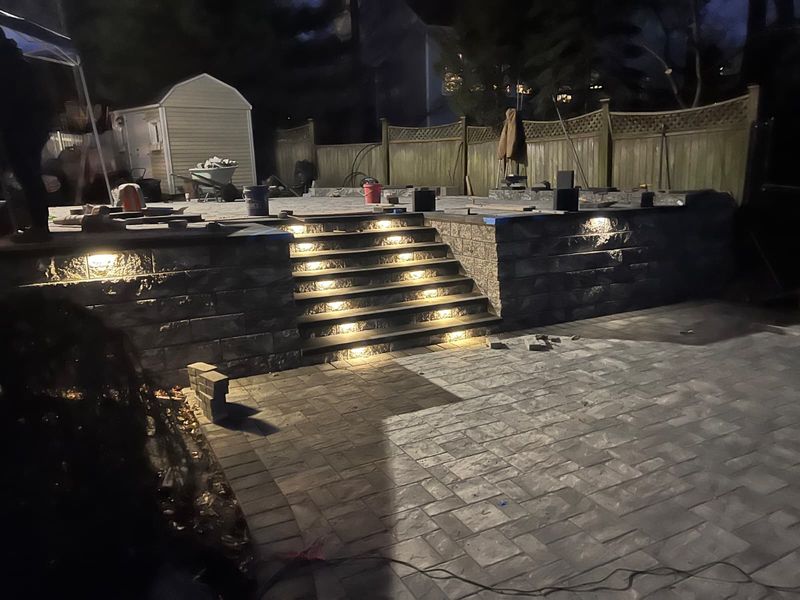 Patio and steps lit at night by JDG Concrete & Construction