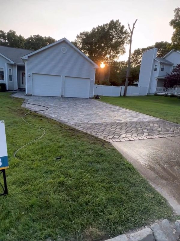 Paver driveway running to a two-car garage by JDG Concrete & Construction