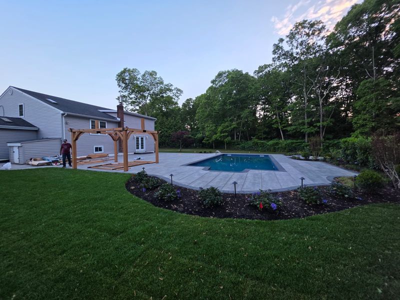 Backyard pool with a pergola and new lawn by JDG Concrete & Construction
