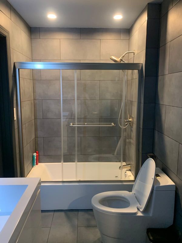 Tub and shower combo with sliding glass by JDG Concrete & Construction